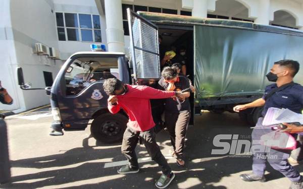 Zul Mazuwan (depan) menutup mukanya dengan baju ketika dibawa ke Mahkamah Butterworth pada Jumaat.