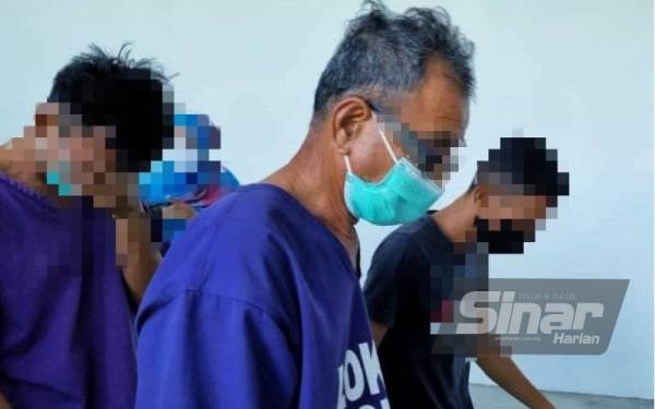 Ayah su (tengah) memakai baju lokap tiba di Mahkamah Majistret Kota Bharu pada jam 9.30 pagi sambil diiringi oleh anggota polis.