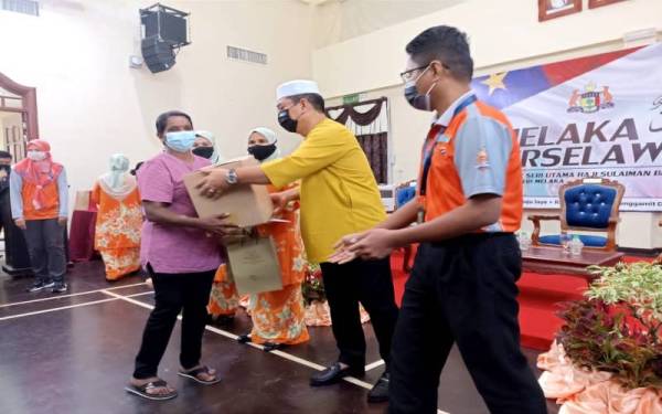 Sulaiman (dua dari kanan) menyampaikan sumbangan kepada seorang penerima di Seri Bendahara, Ayer Keroh Sabtu.