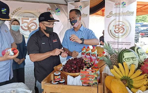 Ronald ( tengah) melihat produk pertanian keluaran FAMA di Pasar Tani Jalan Datin Halimah Johor Bahru pada Sabtu.