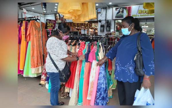 Pramawathy (kiri) semasa melihat baju raya Deepavali di sebuah kedai pakaian di Seremban pada Ahad.