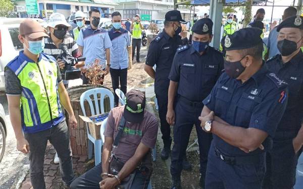 Ayob Khan (kanan) melihat pemandu lori (duduk, tengah) yang ditahan ketika Op Khas Bersepadu di Plaza Tol Skudai pada Ahad.