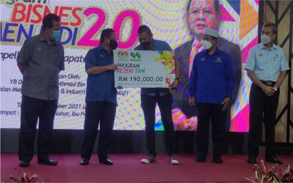 Ahmad (dua dari kiri) menyerahkan replika cek kepada seorang peserta Program Rezeki Petani pada Majlis Perasmian Program Bisnes Menjadi 2.0 di Ibu Pejabat MADA di Ampang Jajar, Alor Setar pada Ahad.