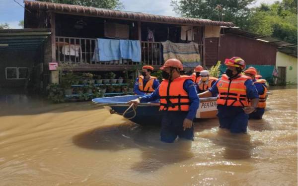 Anggota APM Pendang membantu memindahkan mangsa banjir selepas rumah mereka dinaiki air akibat hujan lebat sejak Khamis lepas. - Foto ihsan APM