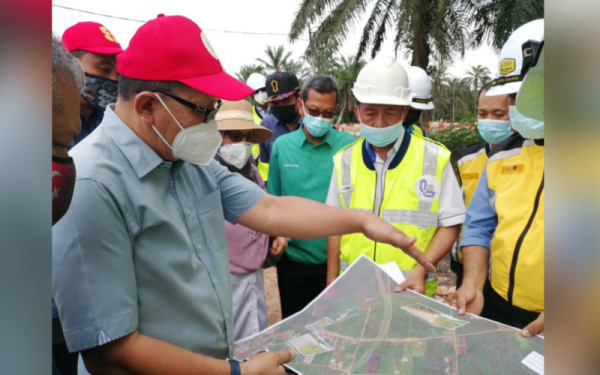 Izham (kiri) melihat pelan projek WCE sewaktu lawatan tapak di di Kampung Seri Cheding, Teluk Panglima Garang pada Selasa.