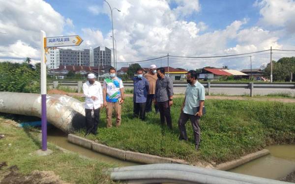 Wan Romani (kiri) meninjau sistem perparitan berdekatan Taman Pulai Jaya, Alor Setar pada Selasa.