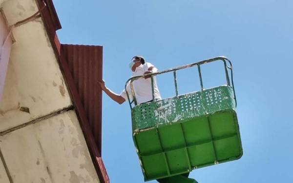 Mohamad Ali menaiki skylift untuk membaiki bumbung SK Kampung Gelam, Melaka pada Rabu.