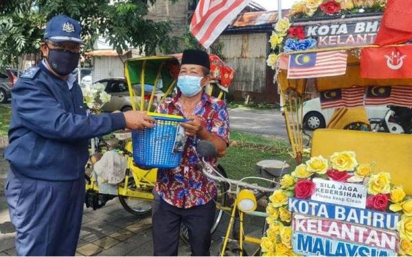 Abdul Wahabi (kiri) menyampaikan sumbangan berkenaan kepada salah seorang penerima di Dataran Muhammadi di sini.