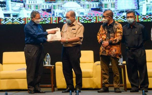 Mustapa (kiri) menyerahkan buku RMK12 kepada Ketua Menteri Sabah, Datuk Seri Hajiji Noor selepas sesi Roadshow Pasca RMK12 di SICC Kota Kinabalu pada Sabtu.