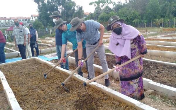 Rodziah (kanan) menyempurnakan gimik Pelancaran Tapak Laman Hijau Strata Kedua Pangsapuri Enggang, Bandar Kinrara, Puchong pada Ahad.