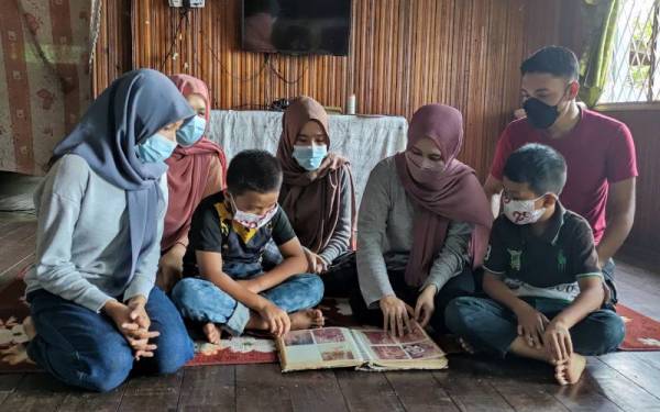 Cempaka Imam (tiga dari kanan) bersama suami dan adik-adik melihat gambar kenangan ibu dan bapanya yang sudah meninggal dunia.