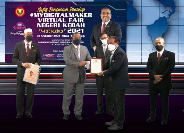 Muhammad Sanusi (dua, kiri) menyerahkan hadiah kepada pemenang pertandingan MyDigitalMaker Virtual Fair Negeri Kedah (MaiReka) di Wisma Darul Aman pada Ahad.