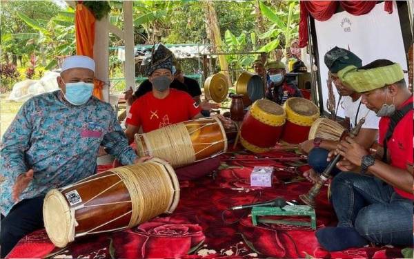 Ariffin (kiri) mencuba bermain gendang ketika menyempurnakan CBT dan Program Pengindahan Pelancongan Daerah Besut di Homestay Kampung Kayu Kelat di Besut pada Ahad.