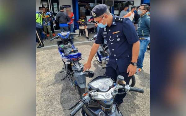 Salah seorang pegawai bertugas menunjukkan antara motosikal yang melakukan kesalahan nombor pendaftaran kenderaan 'fancy'. Foto ihsan PDRM