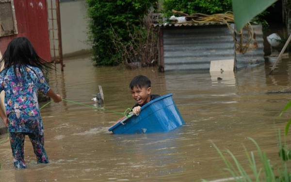 Aidilwafi Izmisyamri, 9, bermain bersama rakannya di halaman rumah mereka yang dinaiki air ketika tinjauan fenomena air pasang besar di sini pada Rabu. - Foto Bernama