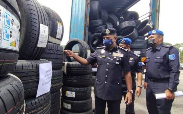 Ayob Khan lakukan pemeriksaan terhadap 727 tayar pelbagai jenama yang dirampas PPM Wilayah Dua dalam sidang media yang diadakan di Ibu Pejabat PPM Wilayah Dua di Johor Bahru hari ini.  - Foto Bernama