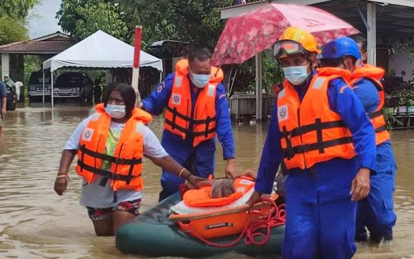 Anggota Angkatan Pertahanan Awam (APM) Kota Setar membantu memindahkan mangsa banjir di Taman Tanjung Bendahara, di sini, pada Khamis.