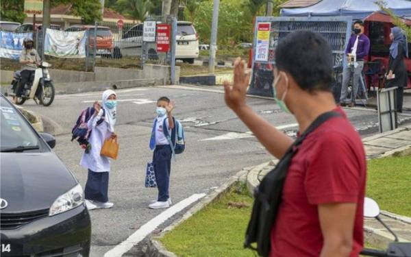 Seorang bapa melambai tangan kepada anak-anaknya ketika menghantar mereka pada hari pertama sesi persekolahan secara bersemuka pada 1 November lalu. - Foto Bernama