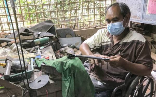 Husmizi yang juga mesra disapa Ngah menyiapkan sarung parang ditempah pelanggannya di bengkel belakang rumahnya di Kampung Alor Melaka, Pulai Chondong. - Foto Bernama