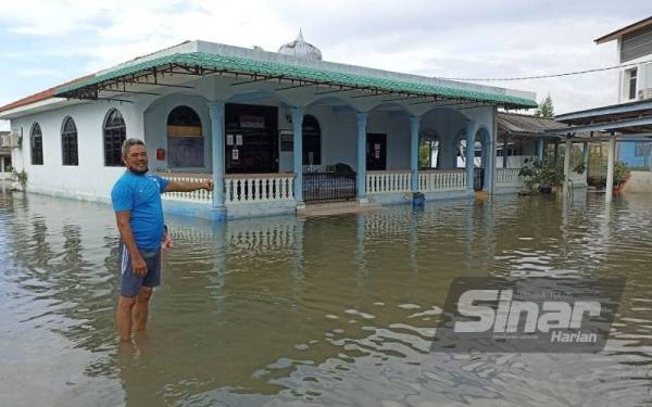 Zazali menunjukkan kawasan pekarangan surau Pekan Kukup yang dipenuhi air akibat air pasang besar pada Ahad.