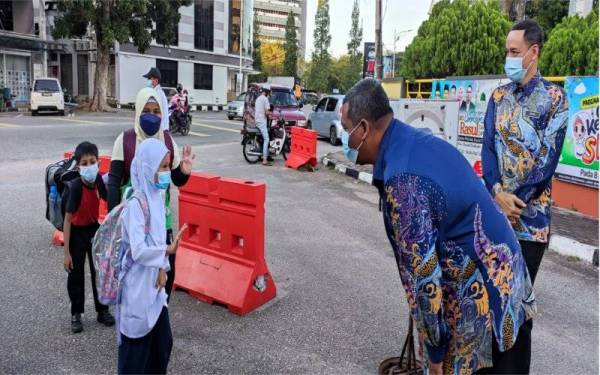 Guru SK Tengku Ampuan Mariam menyambut ketibaan murid di pintu masuk sekolah sebelum mereka diperiksa suhu badan.