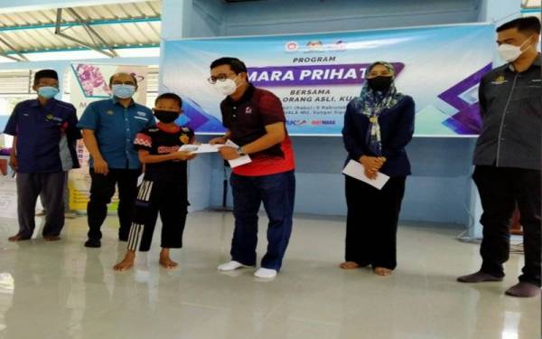 Mohd Nizar menyampaikan bantuan persekolahan kepada seorang murid orang asli pada Program Mara Prihatin Bersama Masyarakat Orang Asli di Surau Pos Kuala Mu, di sini pada Selasa.