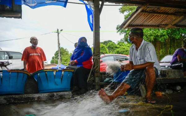 Tuminah (tengah) menyantuni nelayan ketika singgah di Jeti Nelayan Pantai Puteri selepas ke Pasar Nelayan Pantai Puteri. - Foto Bernama