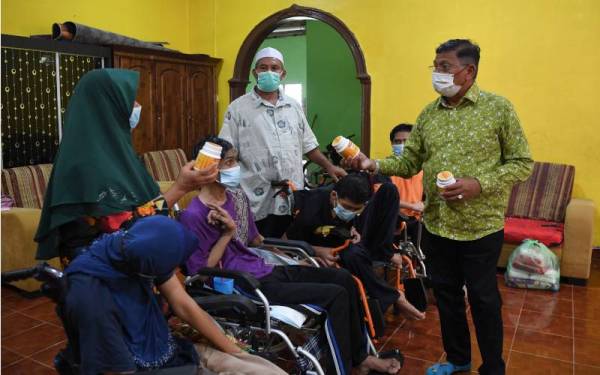 Hanafiah (kanan) semasa melawat empat beradik yang lumpuh seluruh badan akibat penyakit saraf di Kampung Teluk Kalong pada Khamis. - Foto Bernama 