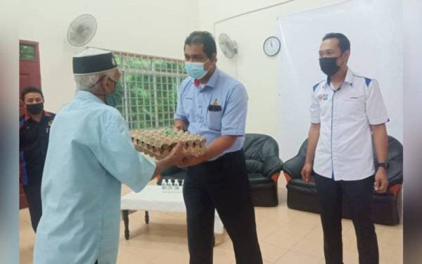 Azanizam (kanan) menyaksikan penyerahan bakul makanan oleh Nik Raisnan di Kampung Gunung Reng, Jeli pada Jumaat.