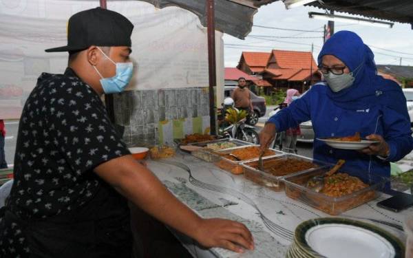 Calon Barisan Nasional (BN) bagi Dewan Undangan Negeri (DUN) N15 Pengkalan Batu Datuk Kalsom Nordin (kiri) mengambil sarapan untuk makan bersama rakan sekolah di sekitar Bukit Piatu.- Foto fail Bernama