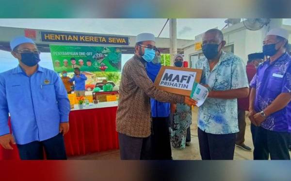 Nik Muhammad Zawawi (dua dari kiri) menyampaian 'one-off' kepada pemandu kereta sewa di Pejabat Kereta Sewa Taman Mahkota, Pasir Puteh pada Sabtu.