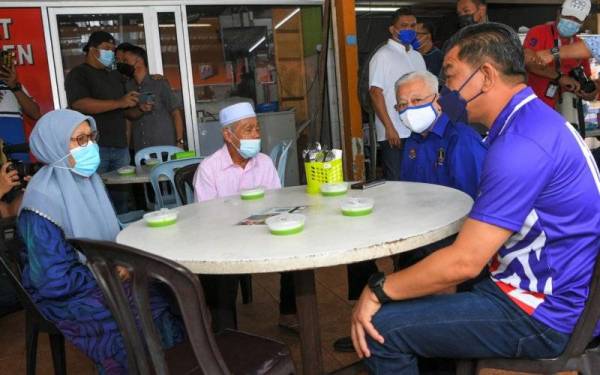 Calon Barisan Nasional (BN) bagi Dewan Undangan Negeri (DUN) N23 Telok Mas Datuk Abdul Razak Abdul Rahman (kanan) bersama Perdana Menteri Datuk Seri Ismail Sabri Yaakob (dua, kanan) meluangkan masa menikmati sarapan pagi bersama pengunjung di Medan Selera Kampung Alai, Telok Mas hari ini. - Foto Bernama