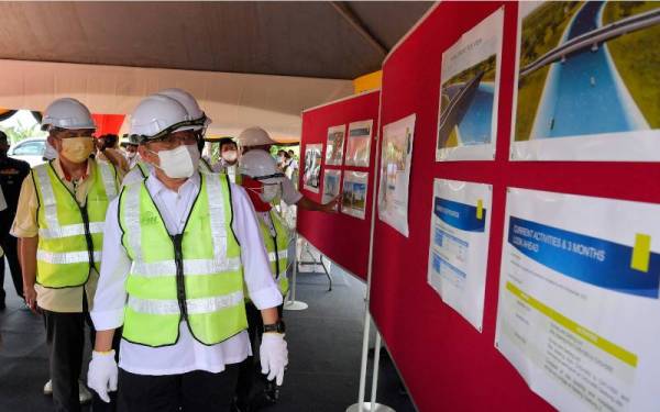 Abang Johari (tengah) melihat lakaran pelan pembinaan pada Majlis Pecah Tanah Projek Jalan Lubok Teranggas-Gedong di sini pada Rabu. Turut kelihatan Menteri Pelancongan, Seni dan Budaya (MOTAC) Datuk Seri Nancy Shukri yang juga Ahli Parlimen Batang Sadong. - Foto Bernama 