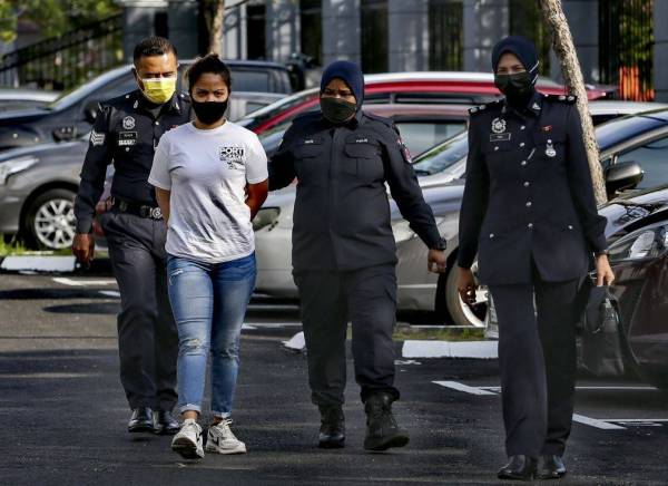 Tertuduh (berbaju putih) diiring polis ketika di mahkamah pada Khamis.