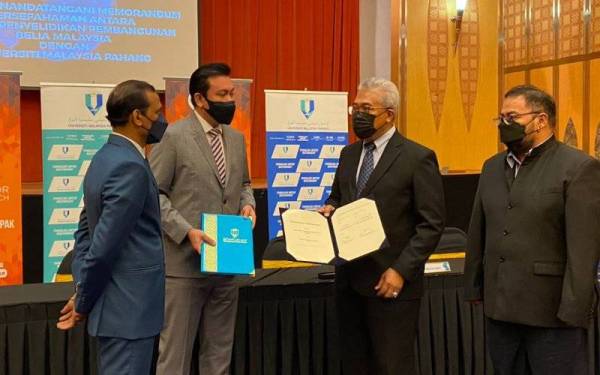 Dr Yuserrie (dua dari kanan) dan Dr Muhammad Mahadi bertukar dokumen MoU dalam majlis yang berlangsung di Dewan Podium, Menara Kementerian Belia Dan Sukan, Putrajaya pada Khamis. - Foto UMP