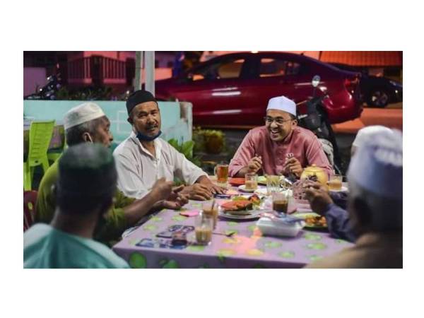 Mohd Rafiq (tengah) bersarapan dengan orang ramai di kedai makan sekitar Telok Mas.