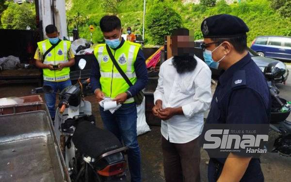 Abd Hamid (kanan) menyoal siasat seorang lelaki warga Myanmar yang menunggang motosikal roda tiga dalam operasi di sekitar Ampang Jaya pada Jumaat.