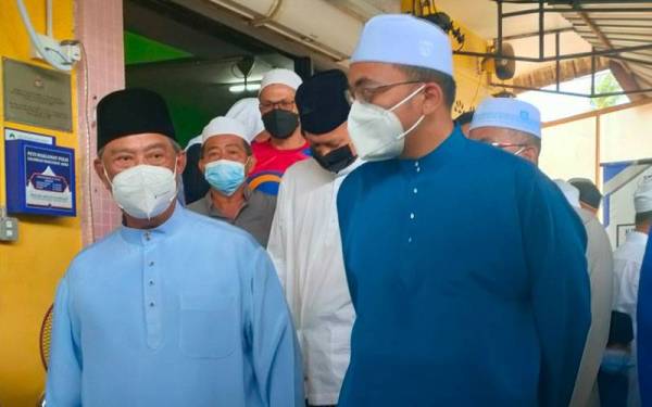 Mohd Rafiq (kanan) mengiringi Pengerusi PN, Tan Sri Muhyiddin Yassin keluar dari Masjid Al- Khairiah, Telok Mas, Melaka pada Jumaat.