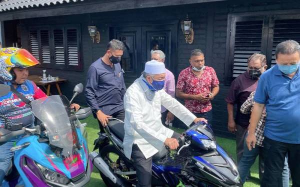 Ahmad Zahid mencuba menaiki motosikal ketika bertemu jentera BN di Bilik Gerakan DUN N02 Tanjung Bidara hari ini sempena PRN Melaka esok. - Foto Bernama