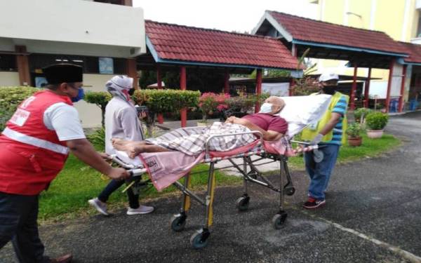 Tawab yang tiba di Pusat Pembuangan Undi Sekolah Kebangsaan Merlimau menaiki ambulans diusung masuk bagi proses pembuangan undi