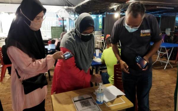 Dr Nor Azimi (tengah) melakukan pemeriksaan ke atas buku rekod pelanggan sebuah kedai makan di Dataran Sekilau di sini ketika Operasi Penguatkuasaan Pematuhan Akta 342 dan PPKHT 2004 pada malam Sabtu.