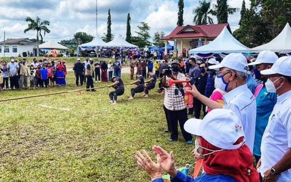 Ismail Sabri (dua dari kiri) merasmikan acara tarik tali sempena Program Merakyatkan Seni Budaya Komuniti Keluarga Malaysia'Hogoh Bera' 2021 di padang Felda Kumai di Bera pada Ahad