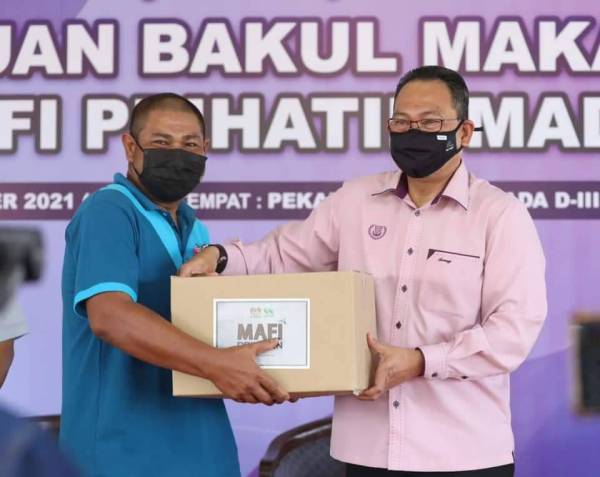 Awang (kanan) menyerahkan bakul makanan MAFI Prihatin-MADA pada seorang pesawah yang terjejas banjir di Pertubuhan Peladang Kawasan (PPK) MADA D-III, Titi Haji Idris, Pendang pada Ahad.