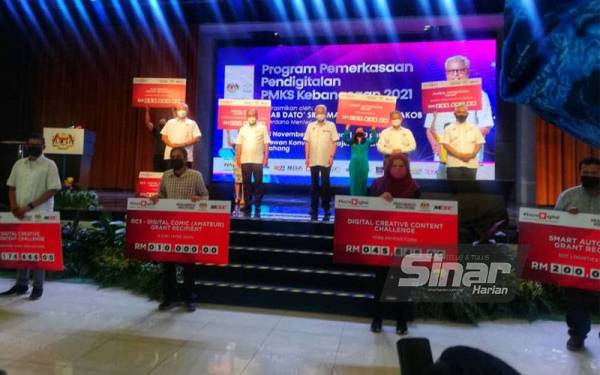 Penerima geran Rakan Digital bersama replika geran masing-masing bergambar kenangan bersama Ismail Sabri (tengah, atas pentas) sempena pelancaran program tersebut di Dewan Konvesyen Majlis Daerah Bera pada Ahad.