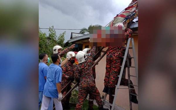 Anggota bomba menurunkan mayat seorang warga emas dari atas bumbung di Felda Pasak, Kota Tinggi, pada Ahad.