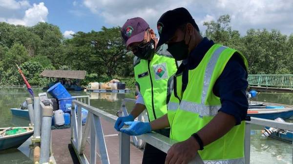 Mohd Famey (kiri) ketika melihat sampel yang diambil pegawai JAS di Jeti Nelayan Kampung Pasir Gudang Baru di sini pada Isnin.