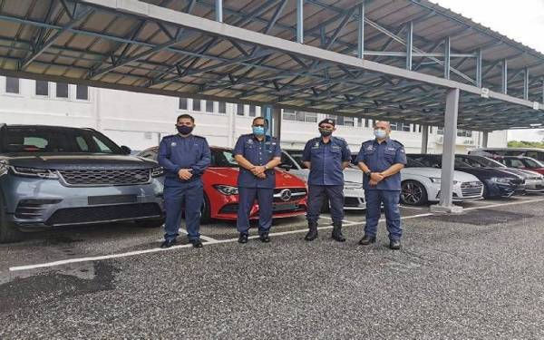 Mohammad Hafiz (dua dari kiri) bersama pegawai JDKM Negeri Sembilan berdiri di hadapan kereta mewah yang dirampas.