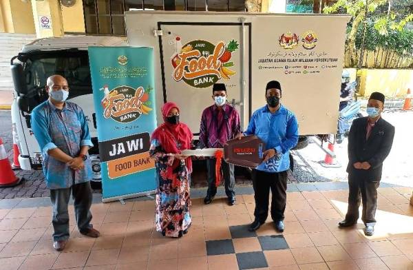 Mohd Ajib (tengah) menyaksikan simbolik penyerahan lori Jawi Food Bank di Kompleks Pusat Islam, Jalan Perdana pada Khamis.
