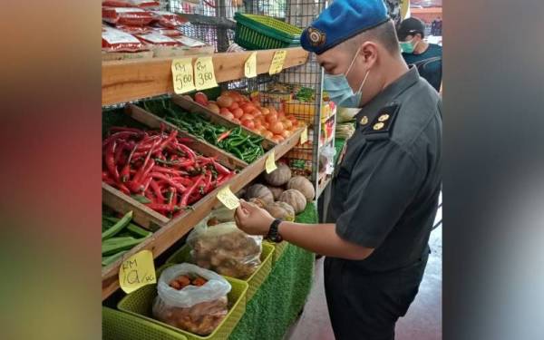 Penguat kuasa memeriksa harga sayur di Pasar Alor Gajah di Melaka pada Jumaat.