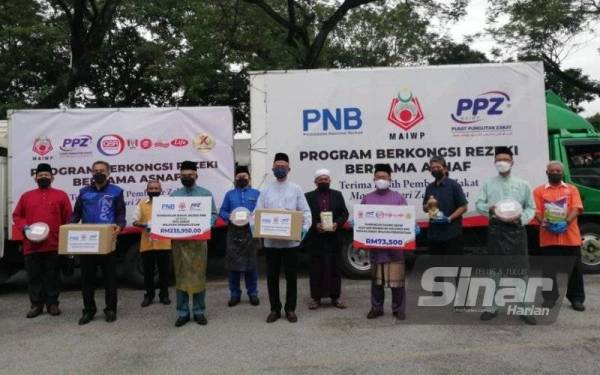 Mohd Daud (tiga dari kiri) dan Kamarudin (tengah) menyempurnakan simbolik penyerahan sumbangan Program Berkongsi Rezeki Bersama Asnaf di Masjid Azzubair Ibnu Awwam, Cheras pada Jumaat.